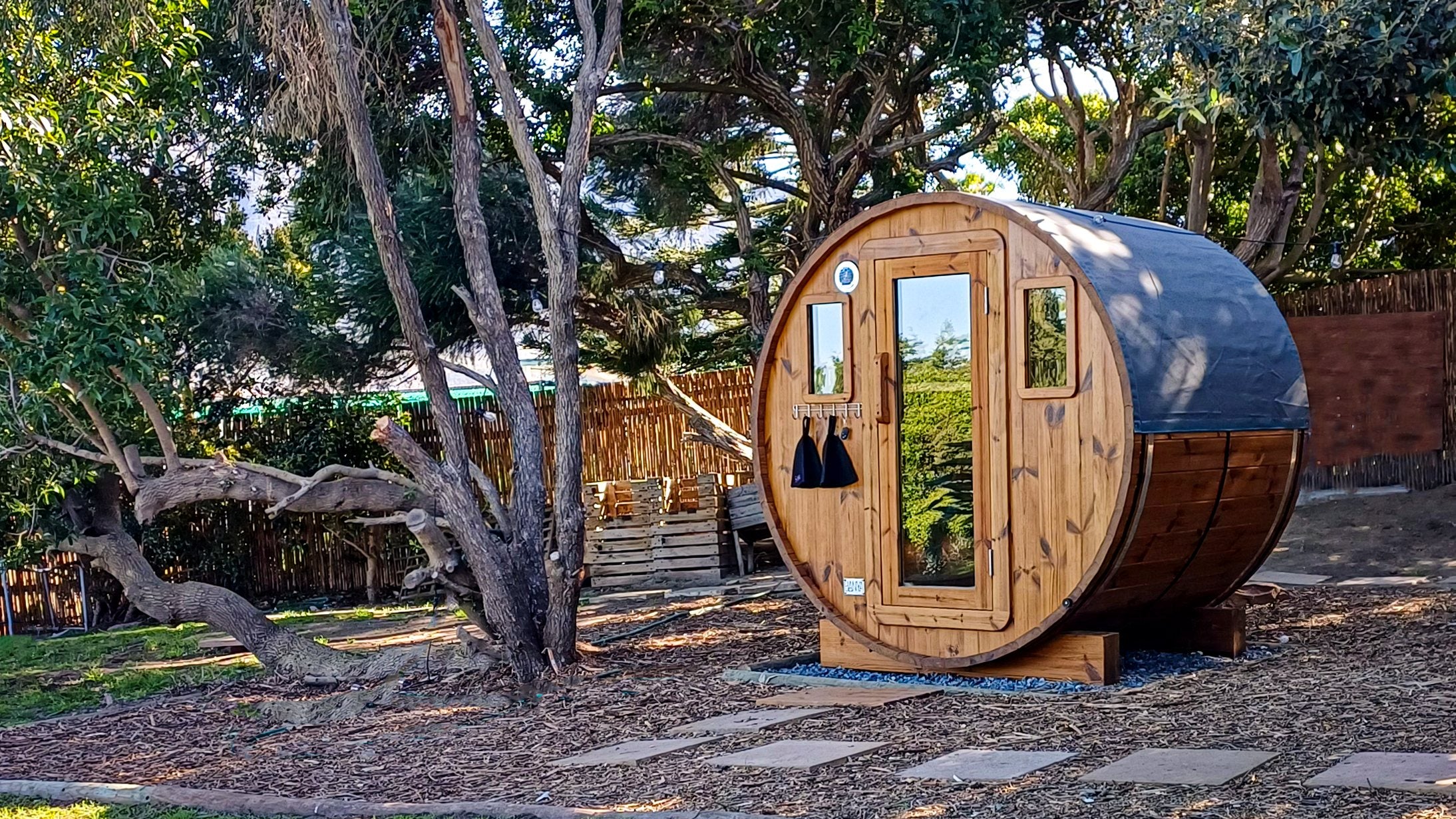 A BANYA barrel sauna under the trees, stepping stones leading to the door