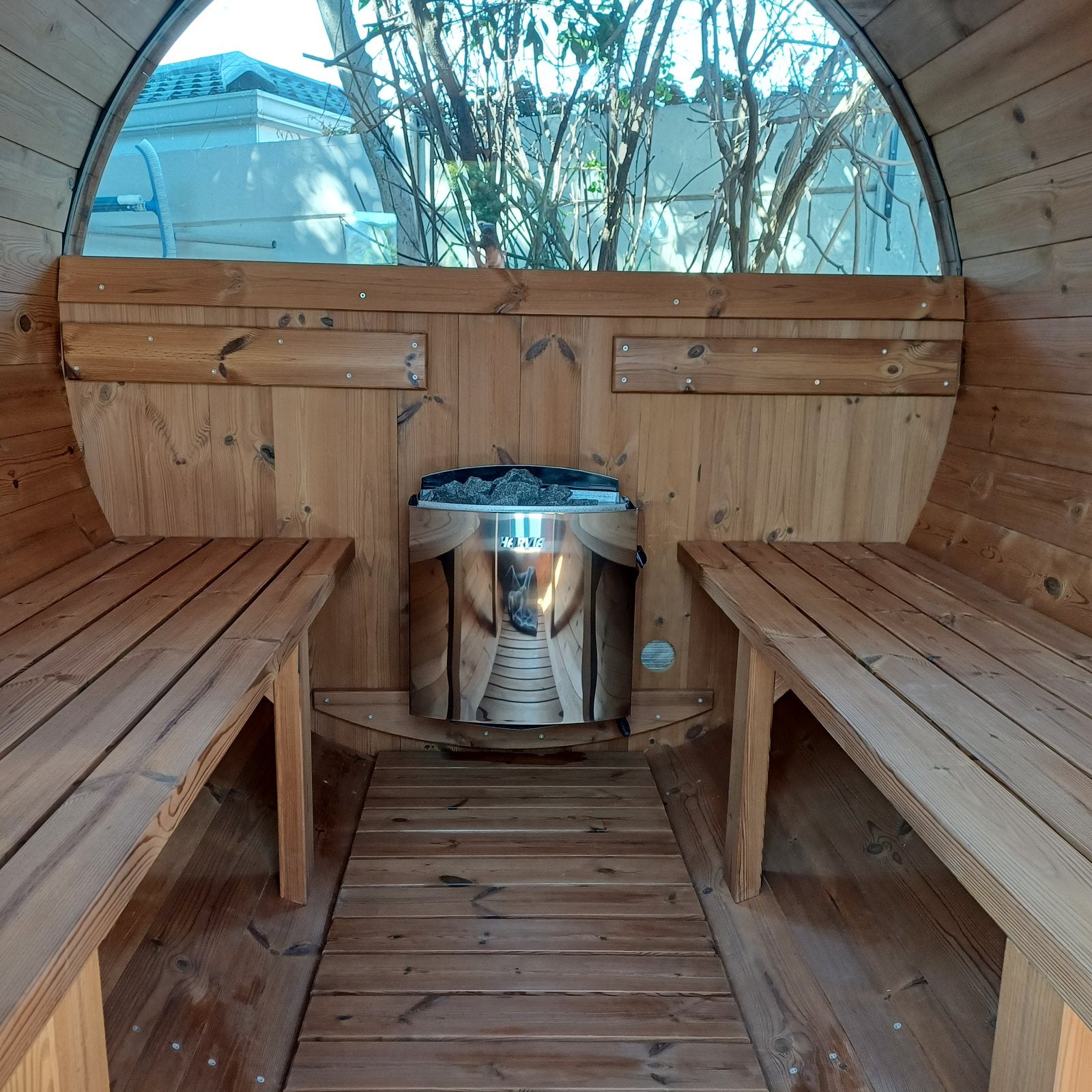 The stainless Harvia heater set between the benches, dome window behind